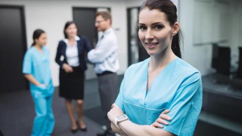 Smiling nurse standing with arms crossed