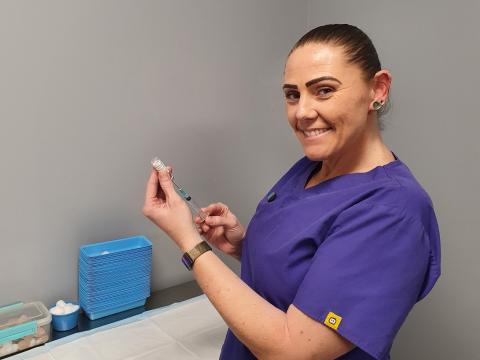 Nurse prepares needle with vaccine